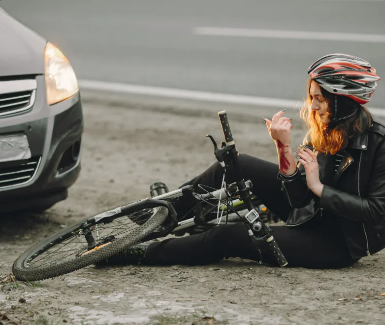 Injured cyclist seated beside a bicycle and car